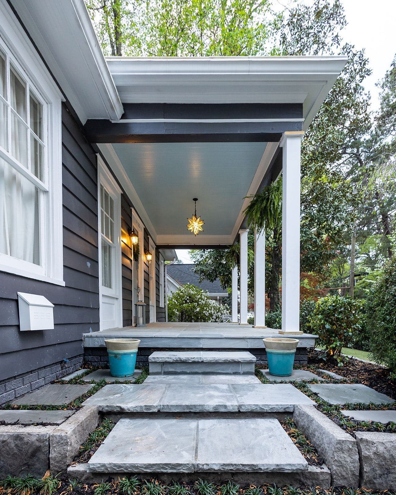 A finished bluestone walkway leading to a covered porch with a warm pendant light